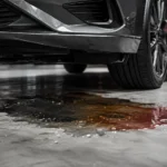 Fluid leaking under a car showing possible oil, coolant or other automotive fluid