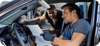 Mechanic checking a logbook inside a car